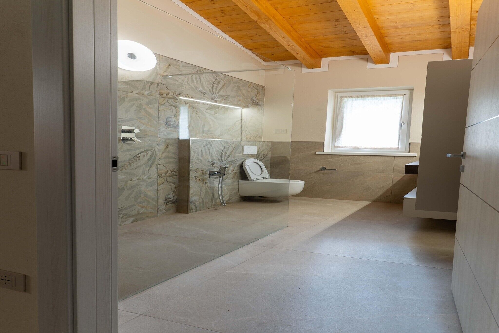 Un baño moderno con cabina de ducha de vidrio, inodoro y ventana que proporciona luz natural.