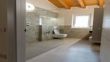 Un baño moderno con cabina de ducha de vidrio, inodoro y ventana que proporciona luz natural.