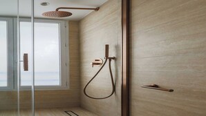 Une douche moderne avec une porte en verre, un porte-serviettes et une fenêtre.