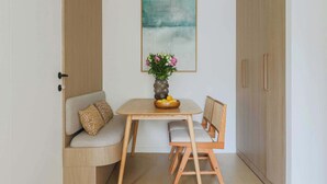 Une petite pièce comprenant un meuble en bois, un canapé avec des coussins à motifs, une table ornée d’un vase de fleurs et une chaise.