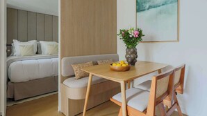 Une chambre moderne avec un lit, un canapé, une table à manger et une chaise. Un vase rempli de fleurs est posé sur la table.