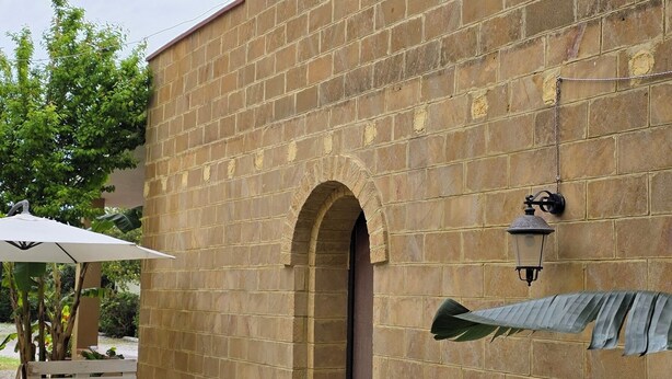 A brick building with a tiled patio, a wooden bench, and a large plant. - Penta Dream House "DORY" (Sicilia)