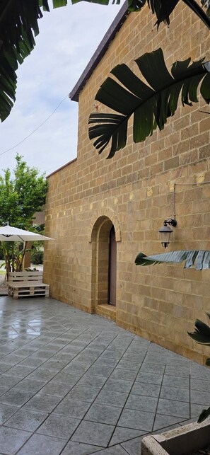 A brick building with a tiled patio, a wooden bench, and a large plant. - Penta Dream House "DORY" (Sicilia)