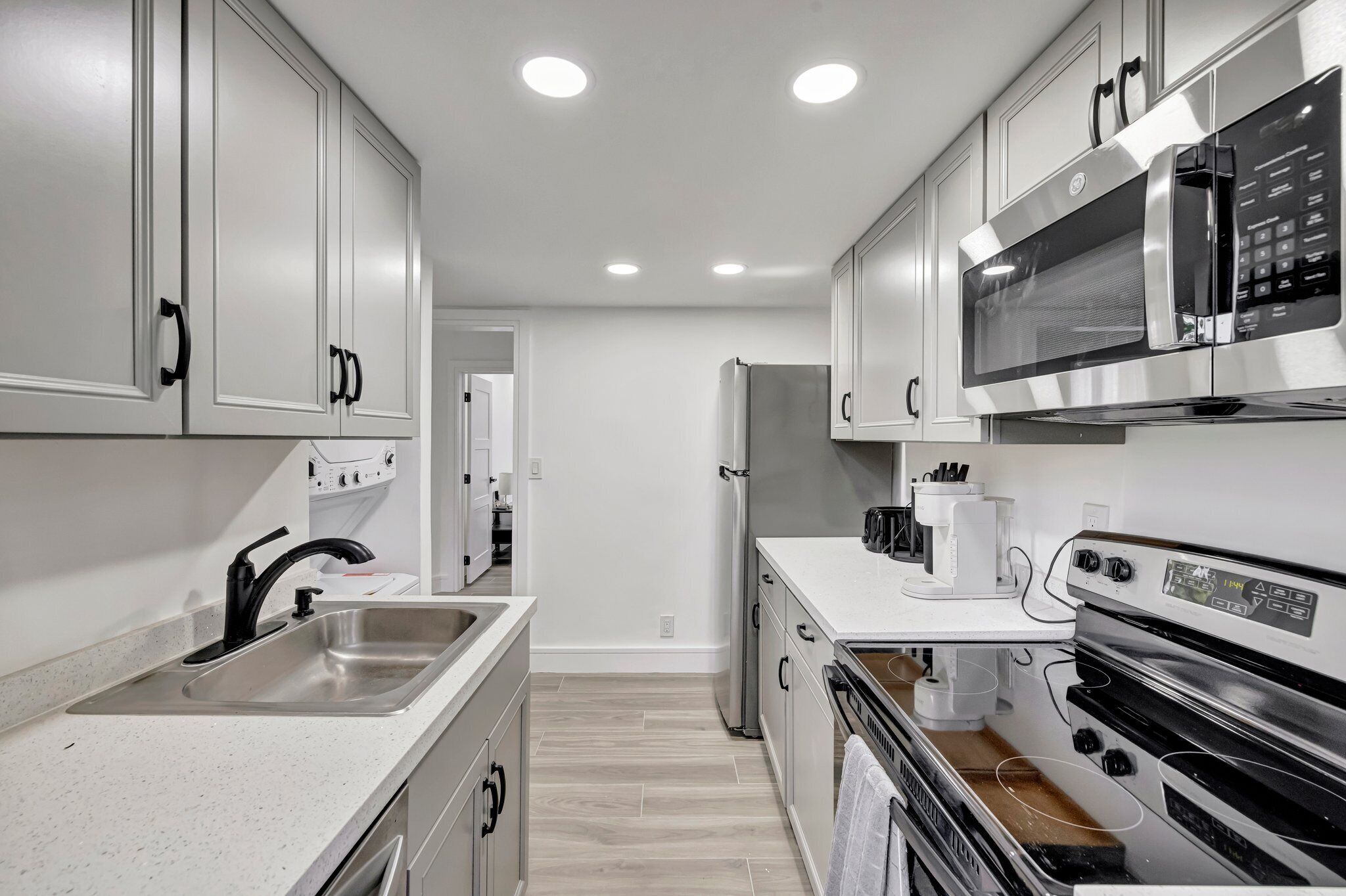 A modern kitchen with white cabinetry, stainless steel appliances, and a white countertop.