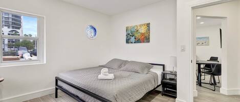 A bedroom with a bed, a window, a door, and a desk with a chair.