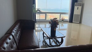 Ein modernes Wohnzimmer mit einer Ledersofa, einem Glastisch und Meerblick durch große Fenster.