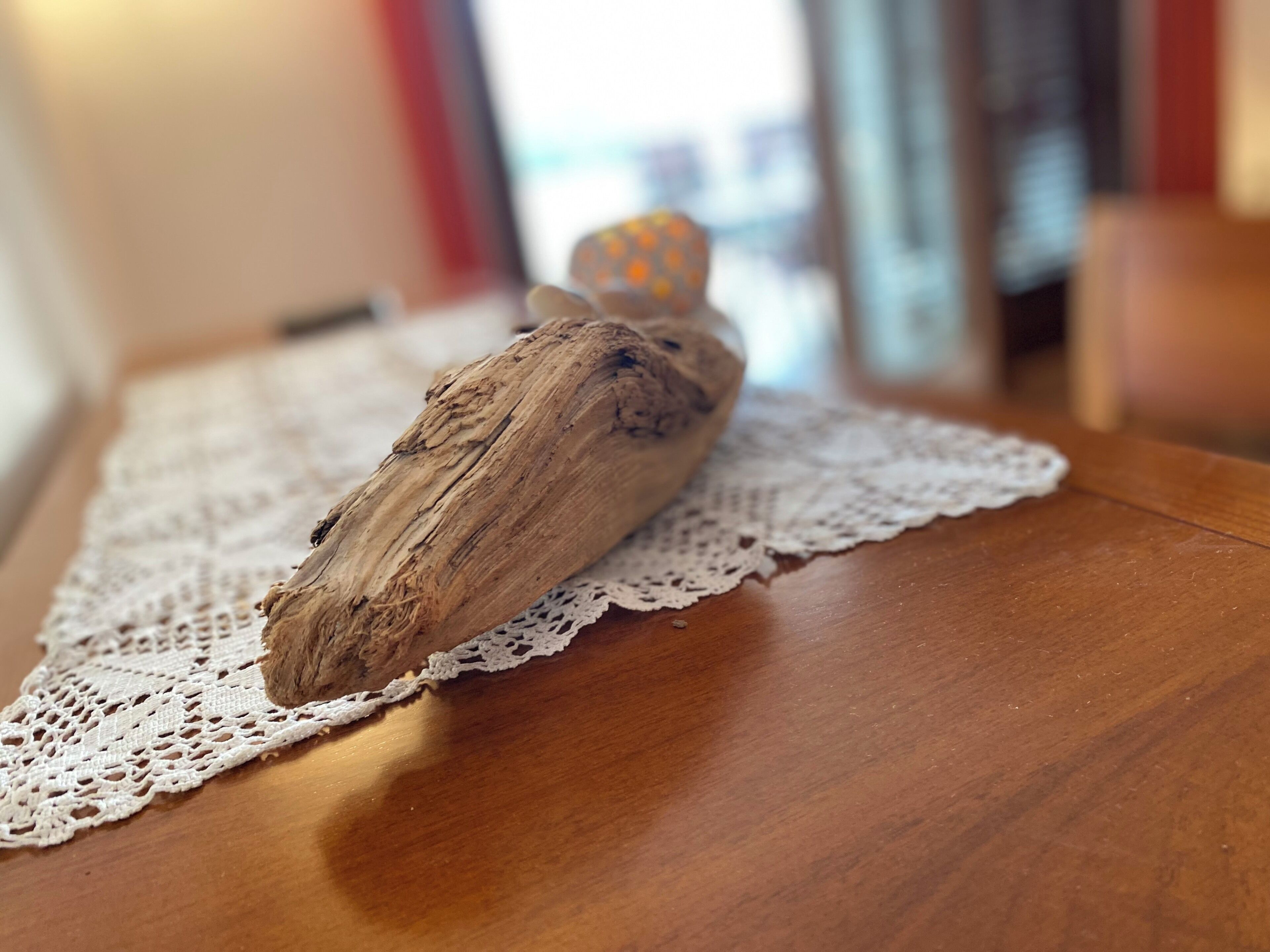 Eine Holzskulptur auf einem Tisch mit einer Spitzenunterlage.