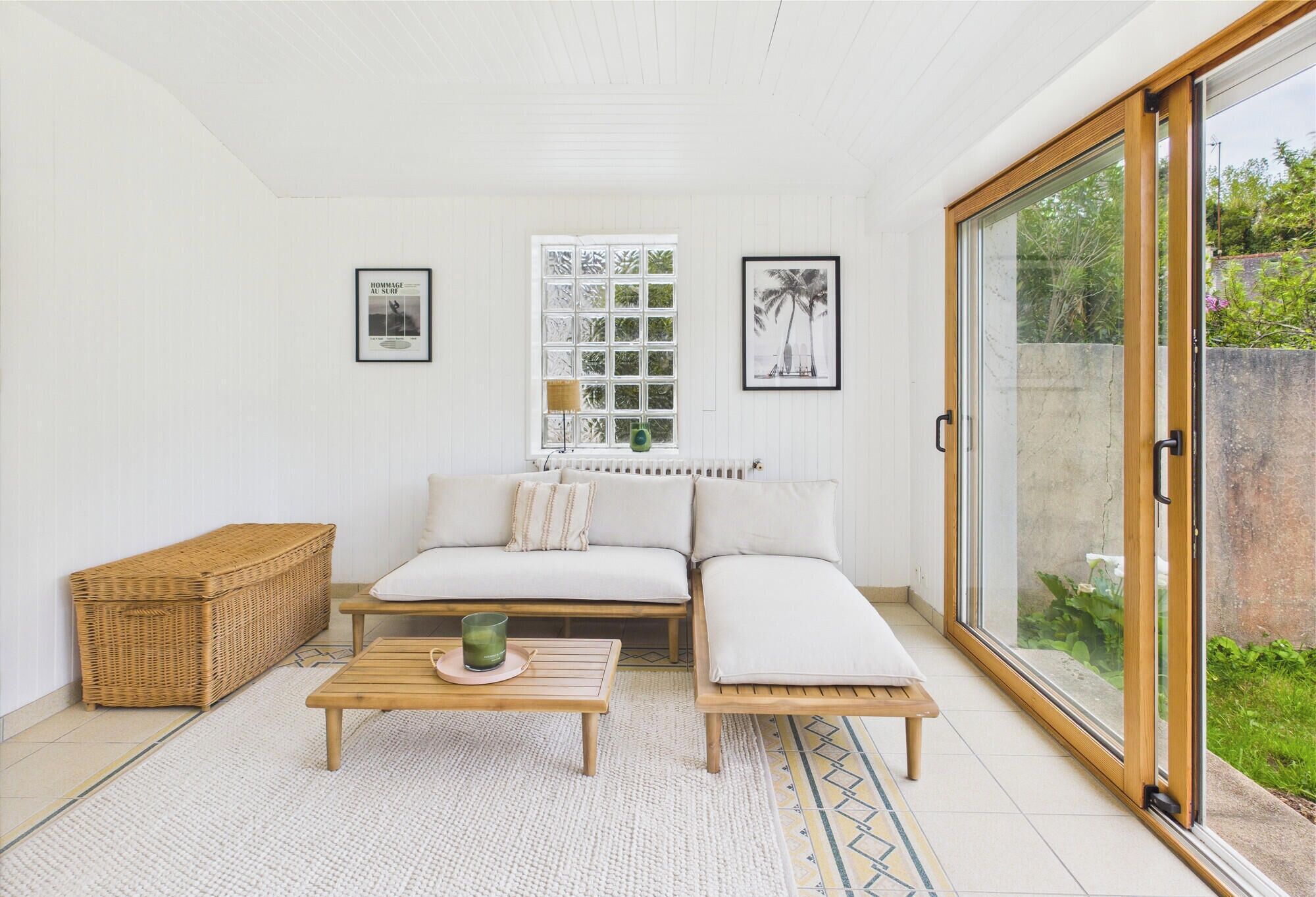 A modern living room with a sofa, a coffee table, and a large sliding glass door leading to a garden.