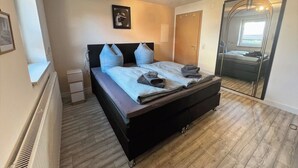 Une chambre à coucher avec un lit, une table de chevet, un miroir et un radiateur.