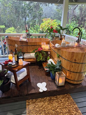 A wooden deck with a seating area, candles, and potted plants.