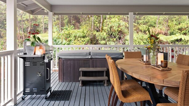 An outdoor patio with a grill, seating, and a view of the surrounding greenery. - Ohia Lehua Hale-Hot Tub-Fireplace-Fire Table-3-Bed, 2-Bath Newly Renovated Home (Volcano)