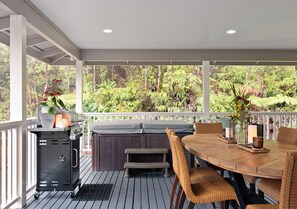 An outdoor patio with a grill, seating, and a view of the surrounding greenery.