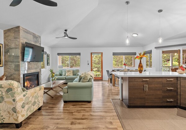 Un amplio salón con chimenea, sofás y una cocina con armarios de madera.