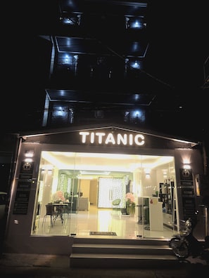 Et hotel kaldet 'Titanic' med en glasfacade, indvendig belysning og synlige siddeområder.