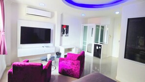 Een moderne woonkamer met een flatscreen televisie, een bank en twee fauteuils.