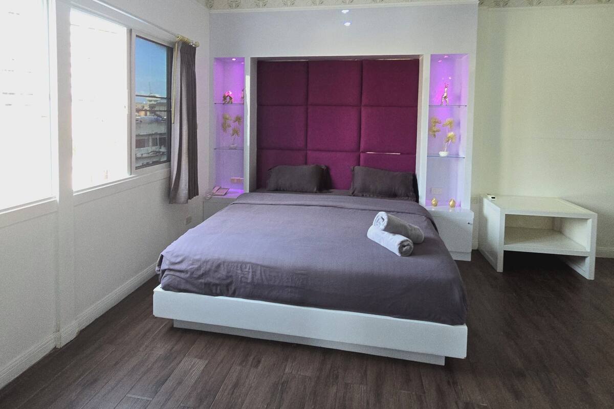 A bedroom with a large bed, a nightstand, and a small table.