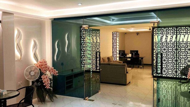 Una sala de estar moderna con un separador de vidrio, un sofá, una mesa de centro y un abanico decorativo.