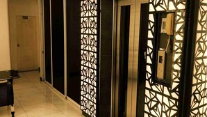 Een hotel lobby met een receptiebalie, een telefoon en een muur met geometrische patronen.