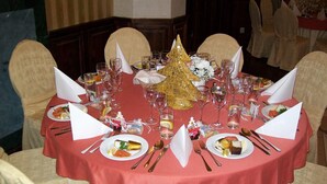 Una mesa redonda con mantel rojo, servilletas blancas y diferentes platos y vasos.