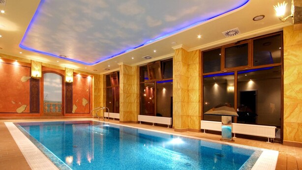 Una piscina interior con vistas despejadas al techo, ventanas amplias y una textura de pared similar al mármol.