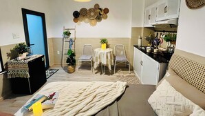 Ein kompakter Wohnbereich mit Küchenzeile, Essbereich und einer Sitzecke mit Sofa und Sesseln.