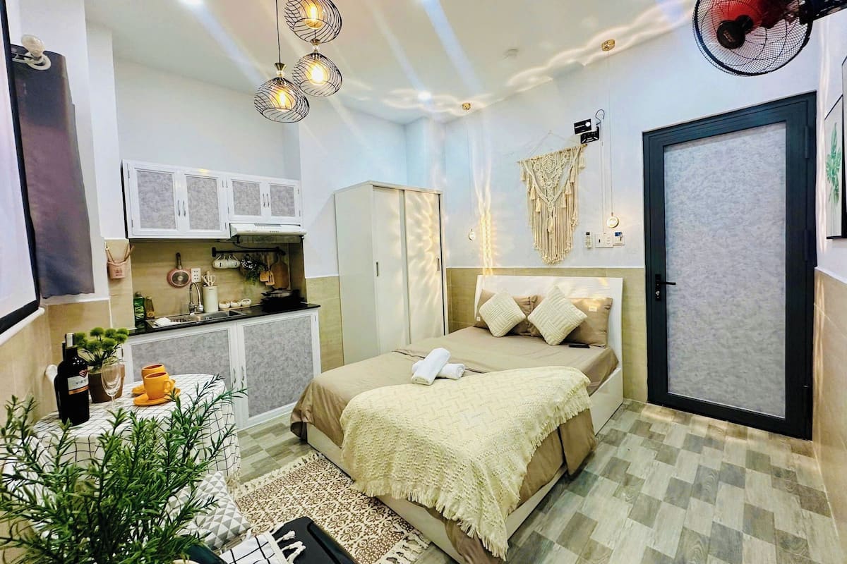 A compact bedroom with a bed, bedside table, and a small kitchenette.