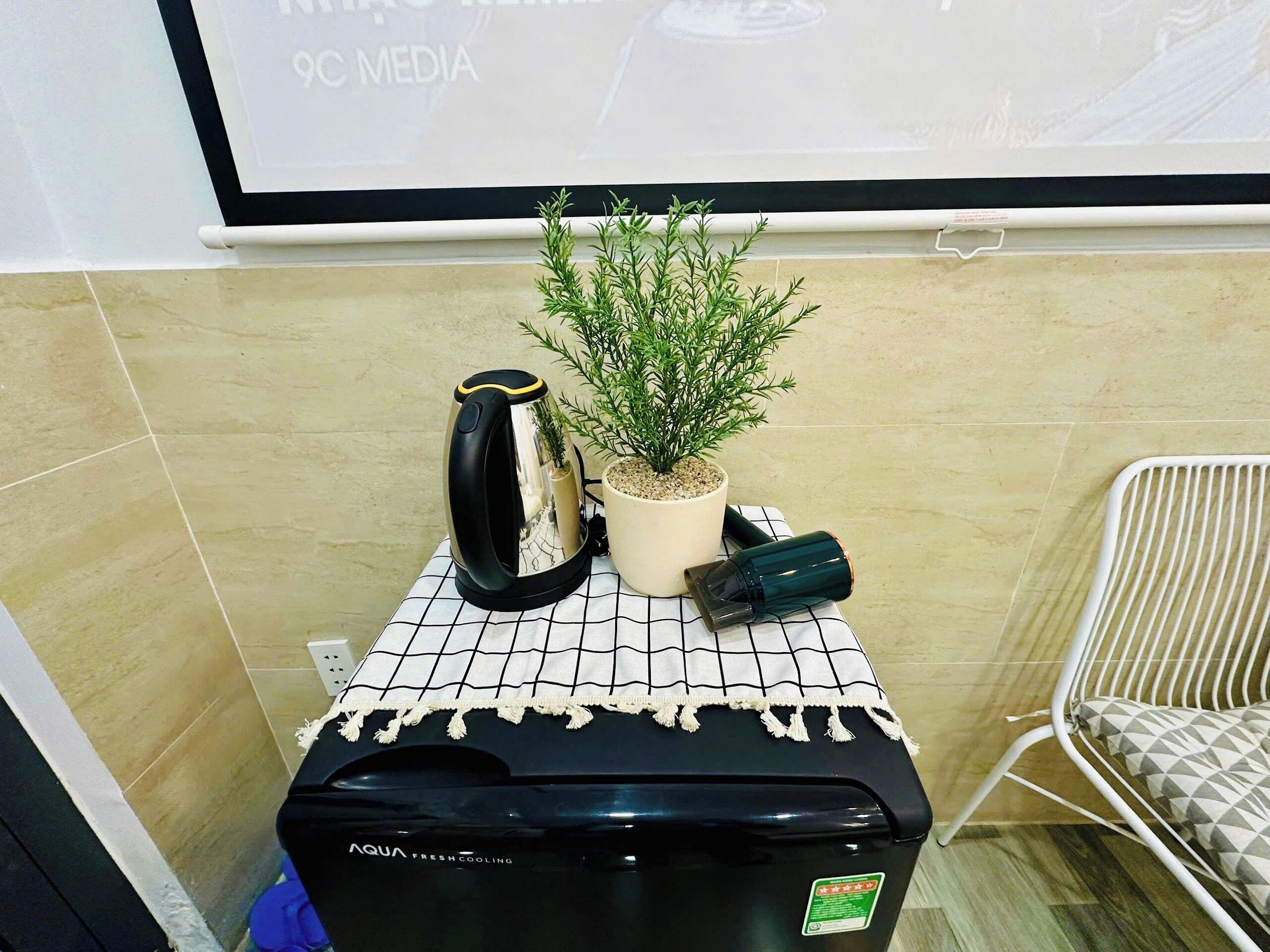 A small kitchenette area with a coffee maker, a potted plant, and a water dispenser on a tiled countertop.