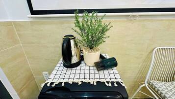 A small kitchenette area with a coffee maker, a potted plant, and a water dispenser on a tiled countertop.