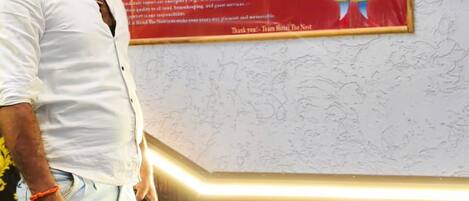 A man standing next to a hotel sign with guidelines for guests and staff.