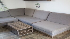 A modern living room with a grey sectional sofa, a wooden coffee table, and a herringbone-patterned floor. - SABLES DU MIDI LOCATION CLIM 3CH 2SDB CAMPING VOS VACANCES (Valras-Plage)