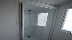A glass-enclosed shower room with a window, a showerhead, and a drain. - SABLES DU MIDI LOCATION CLIM 3CH 2SDB CAMPING VOS VACANCES (Valras-Plage)