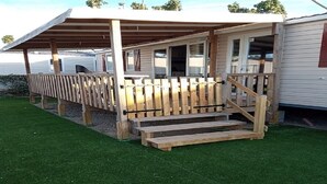 A covered outdoor area with a wooden deck and steps leading to a building. - SABLES DU MIDI LOCATION CLIM 3CH 2SDB CAMPING VOS VACANCES (Valras-Plage)