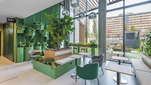 Un espacio interior moderno con paredes verdes, varias zonas de estar y una gran variedad de plantas.
