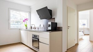 Una cocina moderna con horno empotrado, microondas y cafetera sobre la encimera.