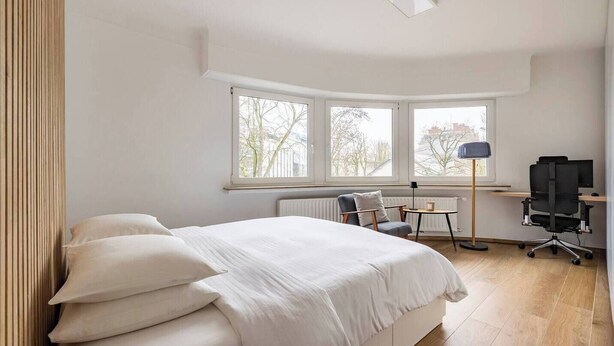 Un dormitorio moderno con una cama grande, un escritorio y una silla.