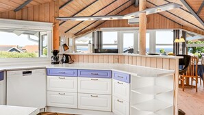 Een moderne keuken met een houten plafond, witte kasten en een groot eiland met blauwe lades.