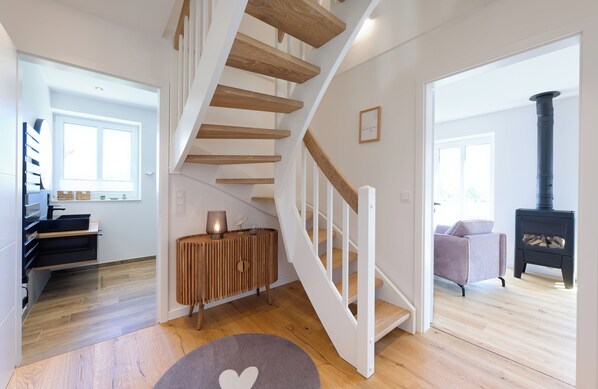 Un intérieur moderne agrémenté d’un escalier en bois, d’un poêle à bois noir et d’un coin salon confortable.