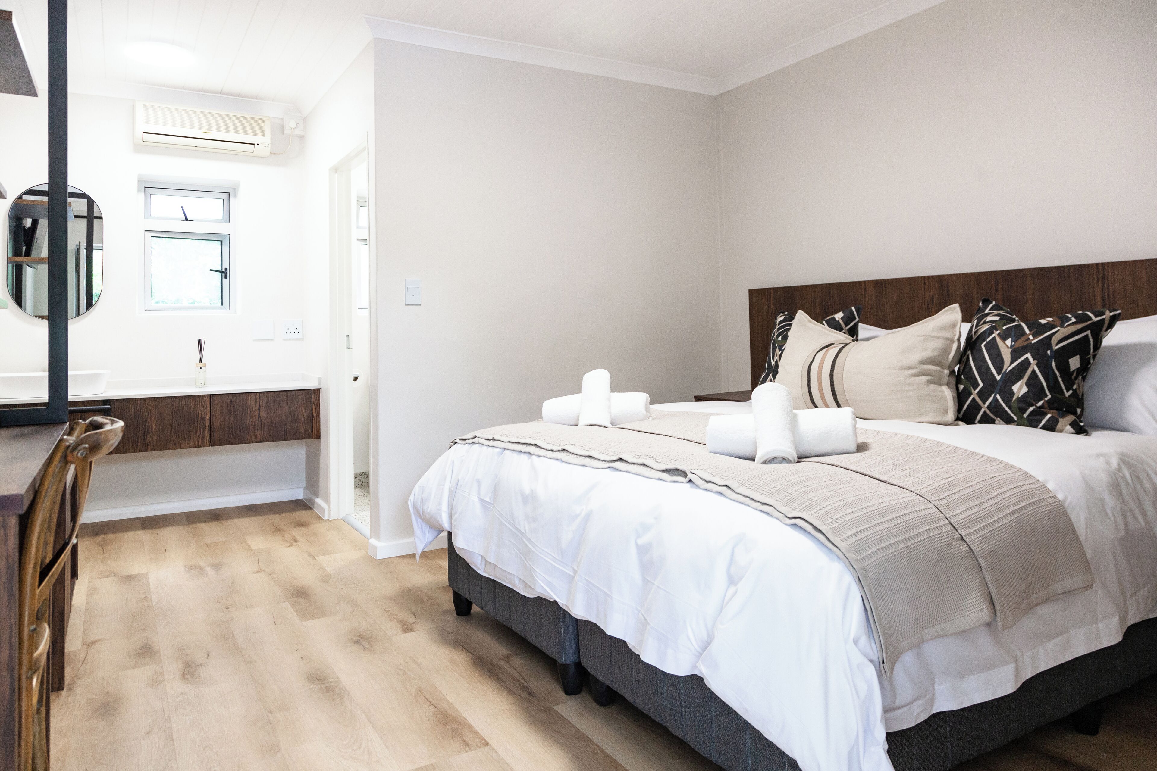 Un dormitorio con cama, mesitas de noche, un espejo y una ventana.