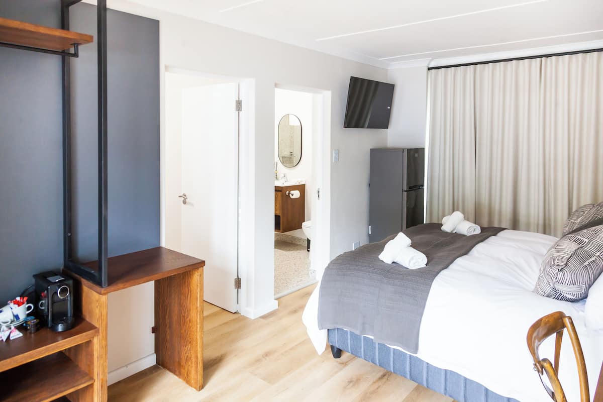 Een hotelkamer met een bed, een televisie, een bureau en een kledingkast.