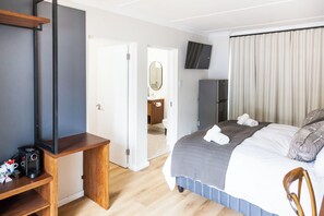 A hotel room with a bed, a TV, a desk, and a wardrobe. - Skinkikofi Guest House (Paarl)