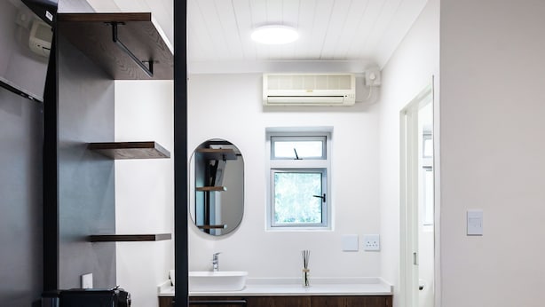 Un baño moderno con un lavamanos blanco, un espejo y una ventana.