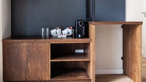 Un escritorio de madera con una pared oscura al fondo, que contiene una cafetera, tazas y una caja pequeña.