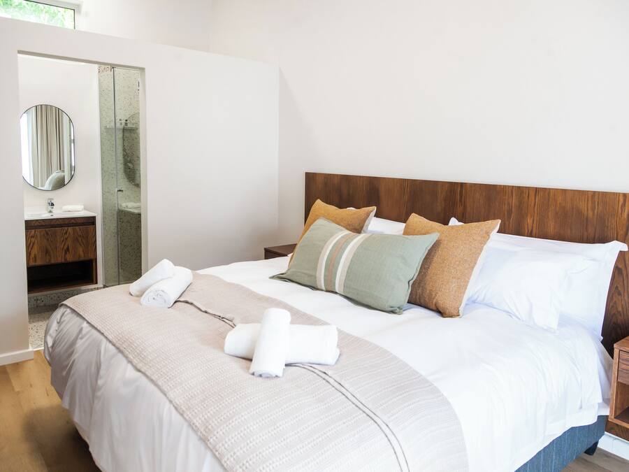 A neatly made bed with white linens, a wooden headboard, and multiple pillows.