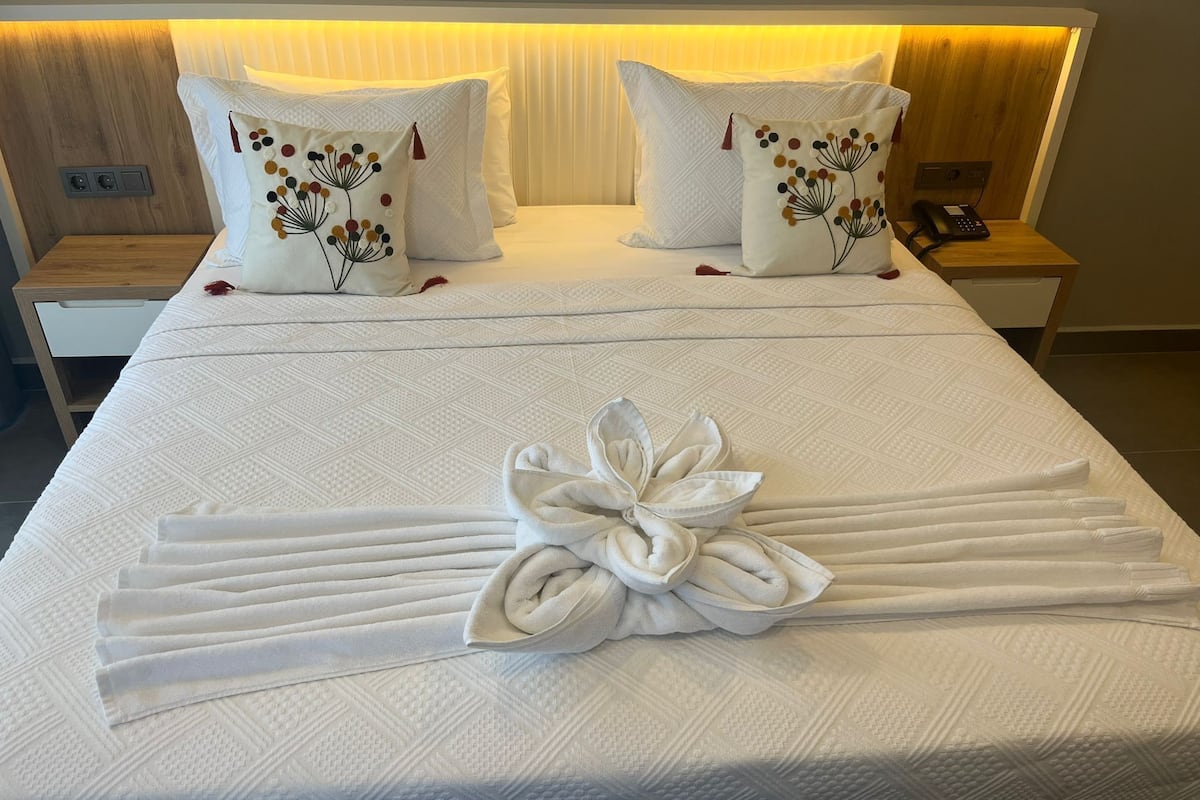 A neatly made bed with a towel arrangement and two decorative pillows.