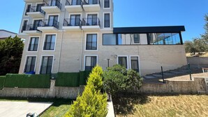 A multi-story building with balconies, large windows, and a modern architectural design. - Ege Vadi Otel (Ayvalik)