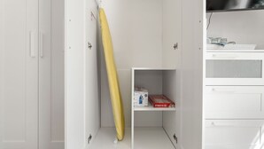 A white room with a white cabinet, a shelf with a box, and a yellow object leaning against the wall. - Dowtown Studio Walkable to Town and Beach (Rincon)