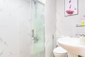 A bathroom with a glass-enclosed shower, a white toilet, and a sink with a mirror.