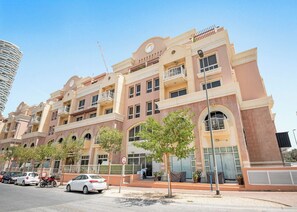 A multi-story hotel with balconies, a pedestrian walkway, and a clear sky.