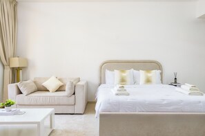 A hotel room with a bed, a sofa, a bedside table, and a lamp.
