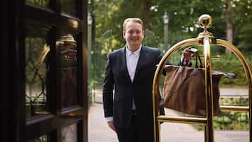 Ein Mann im Anzug steht neben einem goldenen Gepäckwagen.